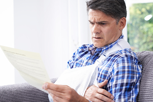 Mature Man Reading Letter About Injury